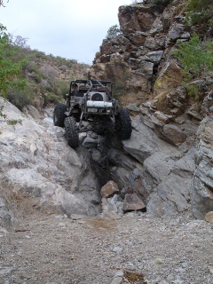 1966 Ford Bronco - Off-road vehicles tackle a challenging rocky ascent on a narrow trail.