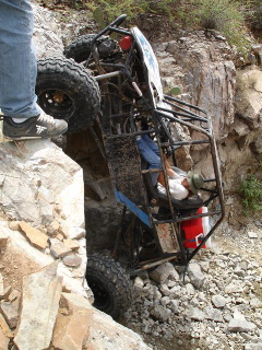 1966 Ford Bronco - Off-road buggy is stuck on a rocky incline, with two people inside.
