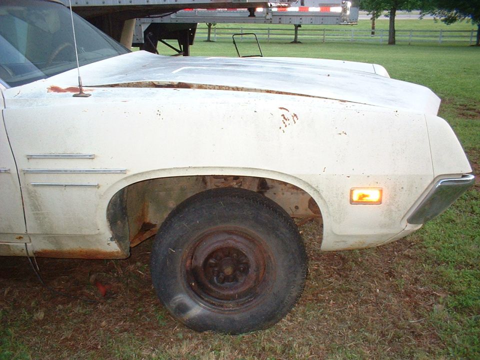 Front fender and wheel of a white 1970 Ford Falcon, showing rust and wear