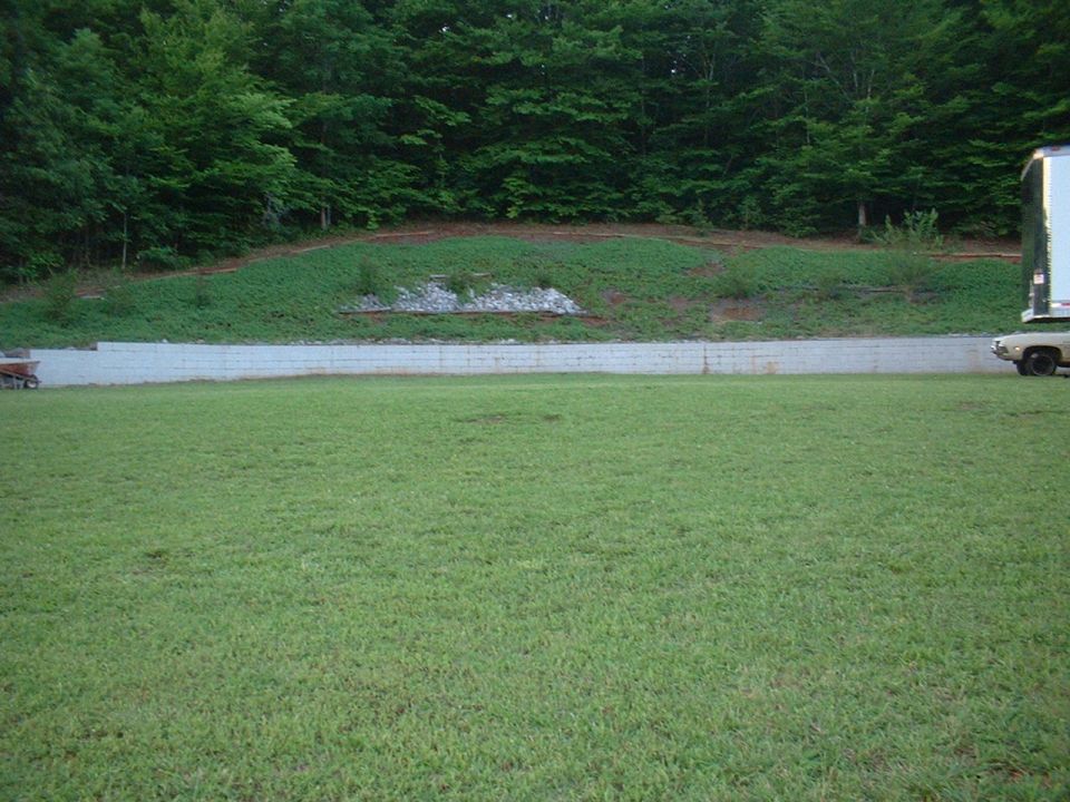 car parked next to a trailer on a grassy area with trees in the background