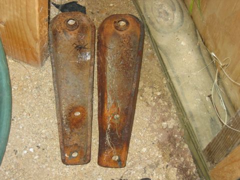 1992 Ford Mustang - Two old, rusty metal brackets are shown on the ground, with a spider on one of them.