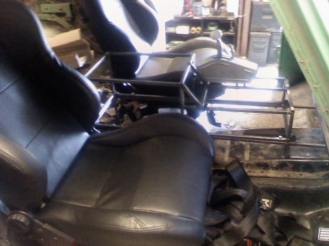 1979 Ford Bronco - The interior of a vehicle shows black bucket seats and a metal roll cage frame, suggesting a rebuild or custom modification.