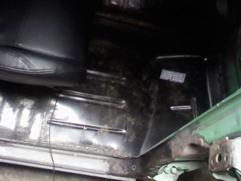 1979 Ford Bronco - Interior view of a vehicle's floor and seat, revealing metal floor panels and signs of wear and tear.