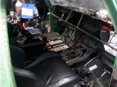 1979 Ford Bronco - The interior of a green vehicle shows extensive modifications, including a roll cage and racing seats.