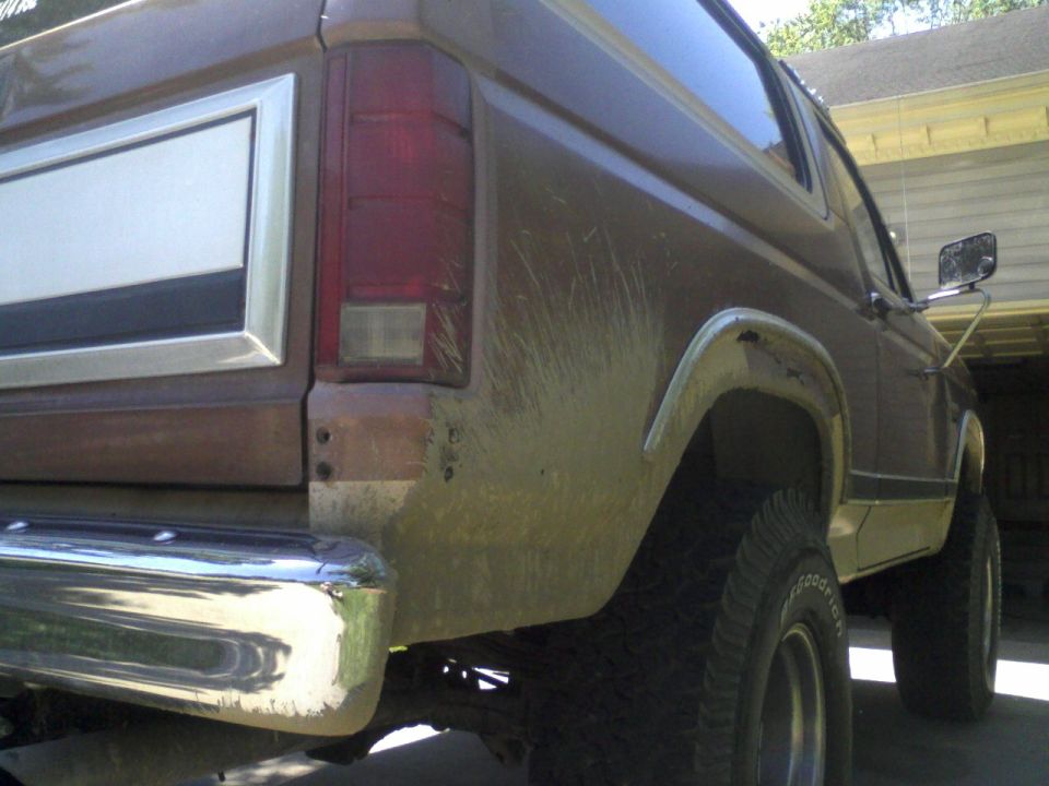 Mud-covered rear quarter of a lifted brown SUV with chrome bumper and BFGoodrich tires