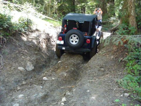 2005 Jeep Wrangler - Jeep Wrangler tackling a challenging off-road path in a wooded area.