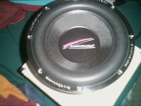 1998 Ford Taurus - A close-up view of a car subwoofer, showing its brand logo and some text around the rim.