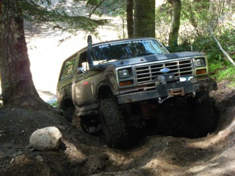 2005 Jeep Wrangler - A Ford Bronco navigates a muddy trail, its tires deep in the dirt.