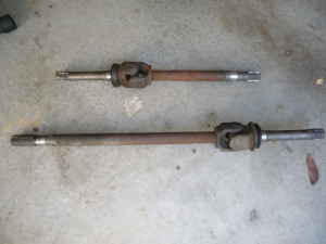 1989 Ford Bronco - Two driveshafts are shown lying on a concrete floor.