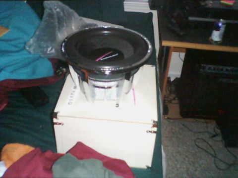 1998 Ford Taurus - A car subwoofer is shown on a box, with a plastic bag and blankets in the background.