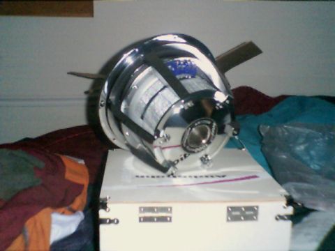 1998 Ford Taurus - A large, shiny car subwoofer sits on top of its packaging box, surrounded by fabric.