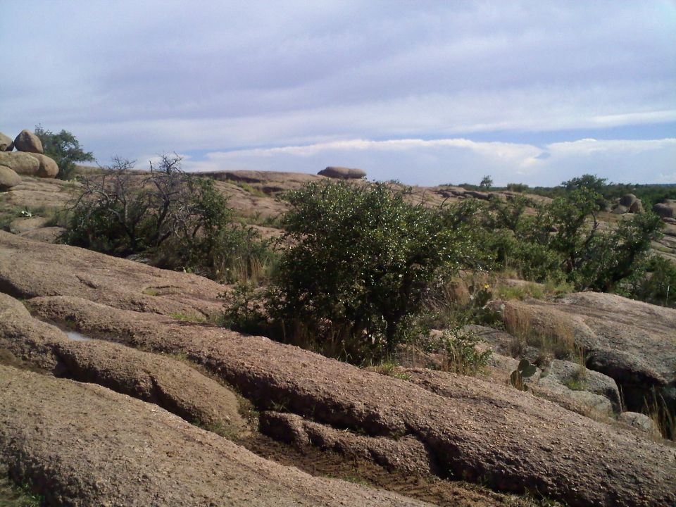 Distant SUV on rocky terrain under a cloudy sky