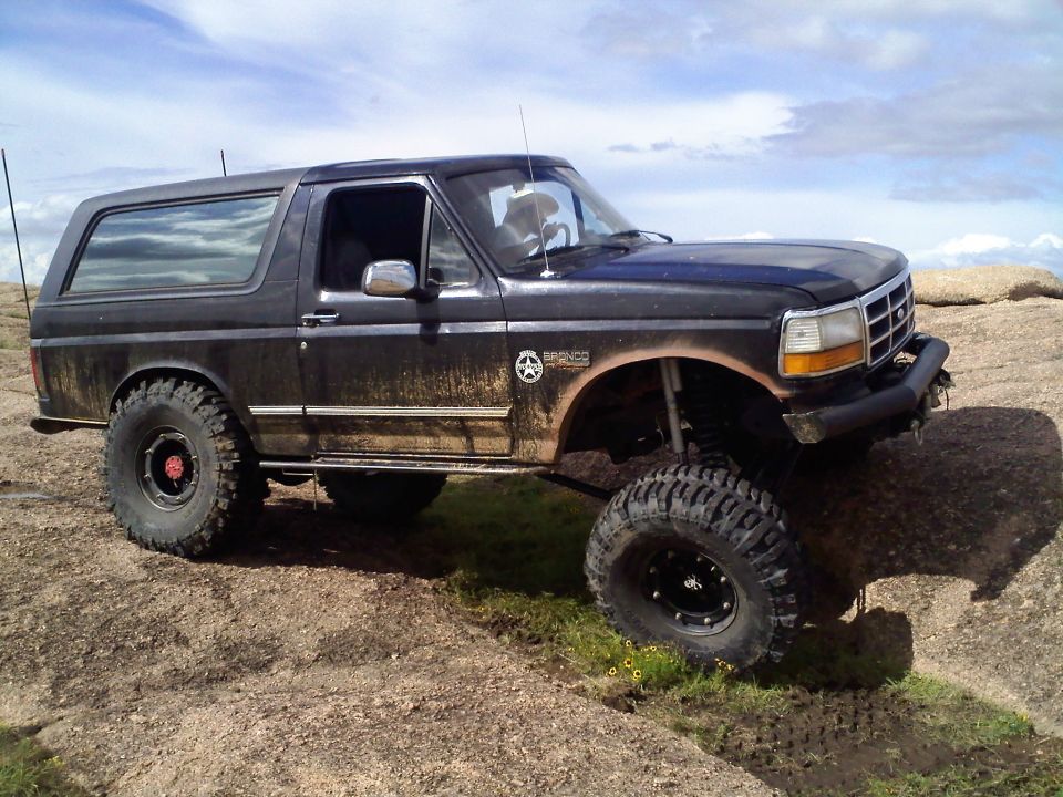 Black 1995 Ford Bronco on rocky terrain, lifted with large tires