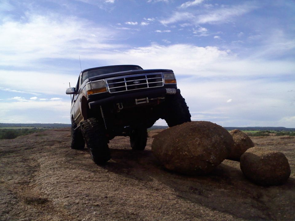 Ford Bronco climbing over rocks on a dirt trail