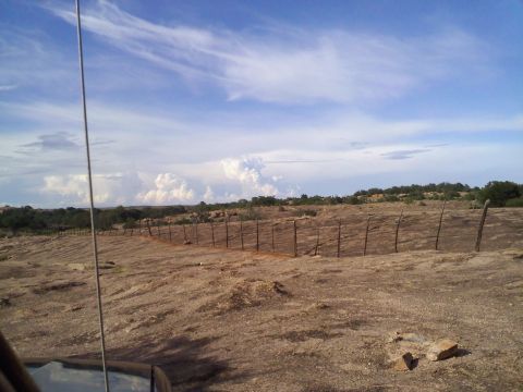 1995 Ford Bronco - View of a dry, rocky landscape with a fence and a vast sky.