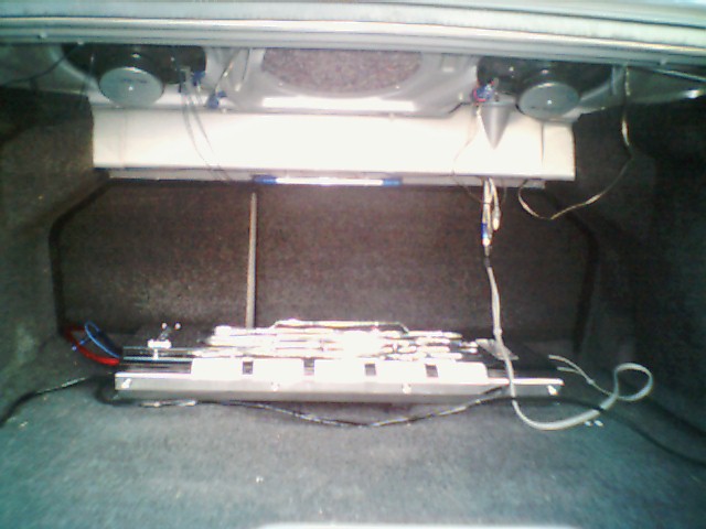 Car trunk with speakers, amplifier, and wiring. A "SUPERMOTORS.NET" watermark is visible