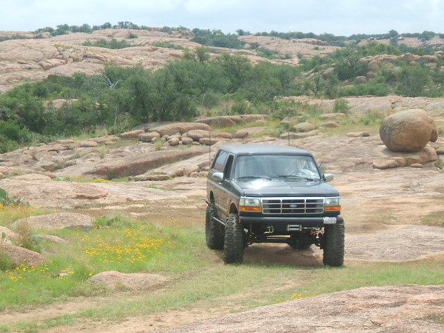 Lifted 1995 Ford Bronco driving on rocky terrain