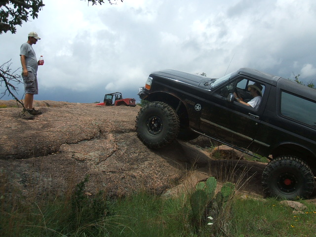 Black 1995 Ford Bronco climbing a rocky hill with another off-road vehicle in the background