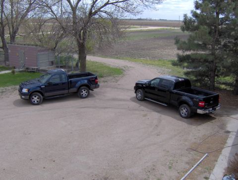 2005 Ford F-150 - Two Ford F-150 pickup trucks are parked in a rural setting with a shed and trees nearby.