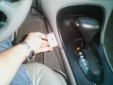 1998 Ford Taurus - Interior view of a 1998 Ford Taurus, showing the automatic transmission shifter and a hand holding a small electronic part.