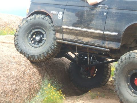1995 Ford Bronco - This modified Bronco is navigating a rocky trail, demonstrating its off-road capabilities.