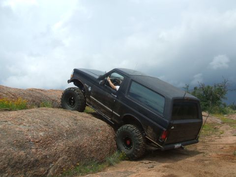 1995 Ford Bronco - A black SUV navigates a rocky terrain under a cloudy sky.