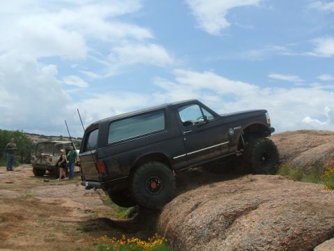 1995 Ford Bronco - Black 1995 Ford Bronco navigating rocky terrain off-road.