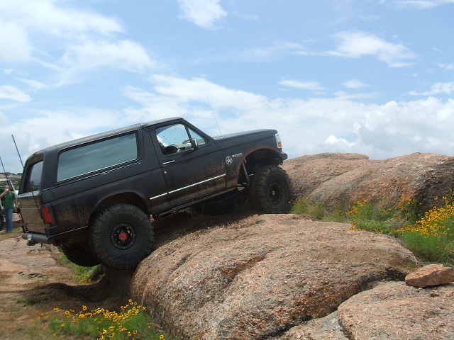 Black Ford Bronco climbing over large rocks on a trail