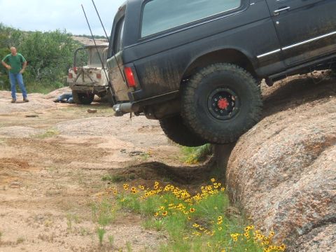 1995 Ford Bronco - A black 1995 Ford Bronco navigates a rocky incline, with another off-road vehicle visible in the background.