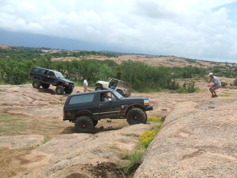 1995 Ford Bronco - Several off-road vehicles, including a 1995 Ford Bronco, traverse a challenging rocky landscape.
