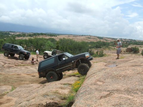 1995 Ford Bronco - Several off-road vehicles navigate a challenging rocky landscape under a cloudy sky.