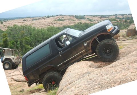 1995 Ford Bronco - A black 1995 Ford Bronco navigates a steep, rocky terrain during an off-road excursion.