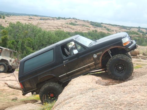 1995 Ford Bronco - 1995 Ford Bronco navigating a rocky off-road trail with another vehicle present.