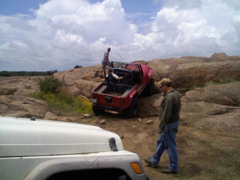 1995 Ford Bronco - Two off-road vehicles navigate a rocky landscape under a cloudy sky.