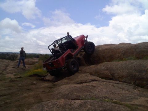 1995 Ford Bronco - A red Jeep navigates a rocky terrain, its off-road capabilities.
