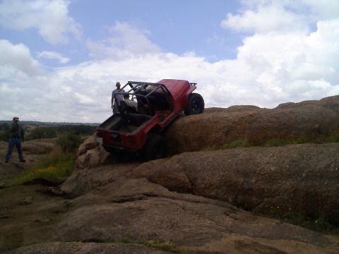 1995 Ford Bronco - Off-road jeep navigating a rocky terrain under a cloudy sky.