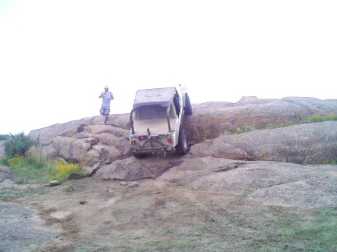1995 Ford Bronco - A person watches as an off-road vehicle navigates a challenging rocky terrain.