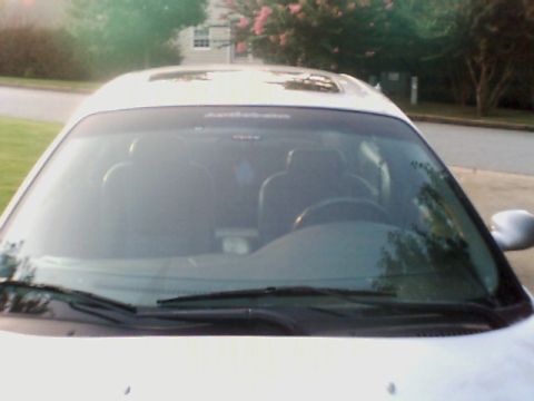 1998 Ford Taurus - The front of a white sedan is shown, with trees and a house in the background.