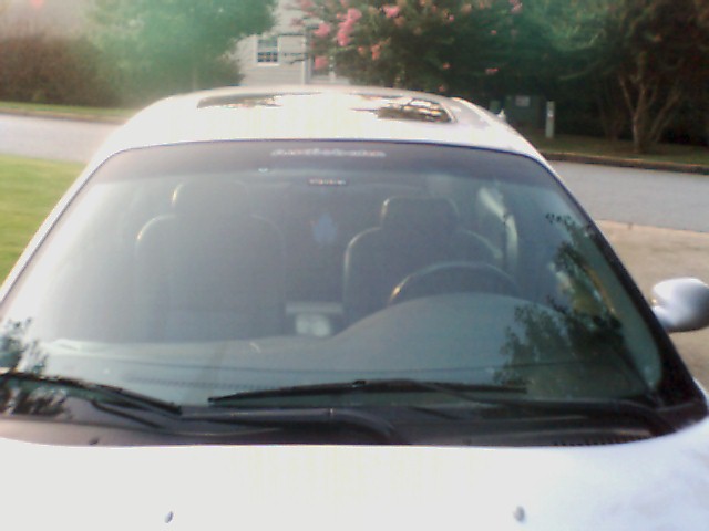 Front view of a white sedan with a sunroof. Interior visible through windshield