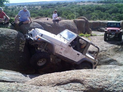 1995 Ford Bronco - White Jeep Wrangler navigating a rocky trail, with another Jeep visible in the distance.