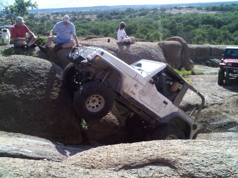 1995 Ford Bronco - A Jeep Wrangler navigates a rocky trail with spectators observing the off-road adventure.