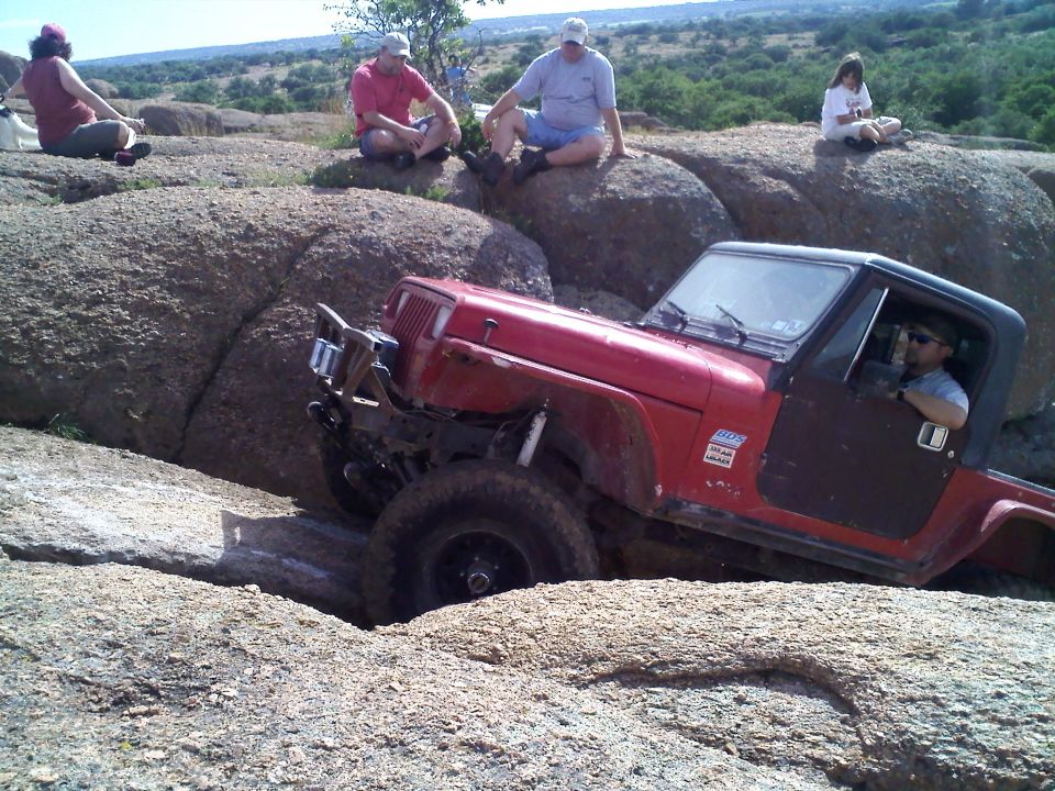 Red Jeep Wrangler navigating rocky terrain