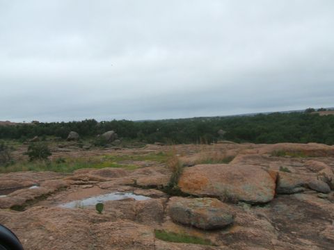1995 Ford Bronco - A wide view of a rocky, arid landscape with sparse green vegetation and a cloudy sky overhead.