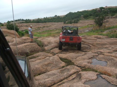 1995 Ford Bronco - Off-roading adventure in a red Jeep Wrangler on a challenging rocky landscape.