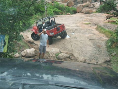 1995 Ford Bronco - Two off-road vehicles navigate a rocky trail with a man taking a photo of one of one of them.