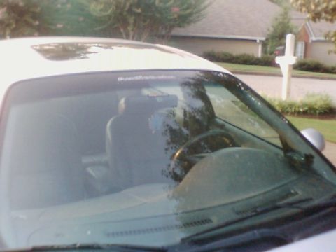1998 Ford Taurus - The interior of a white sedan is visible through the windshield, showing the dashboard and seats.