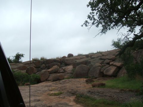 1995 Ford Bronco - View from inside a vehicle looking out at a rocky, tree-covered hillside on an overcast day.