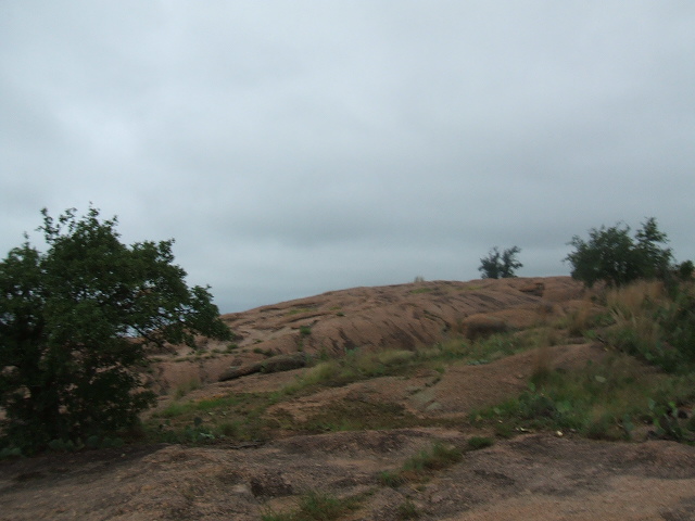 rocky hill with sparse trees under a cloudy sky