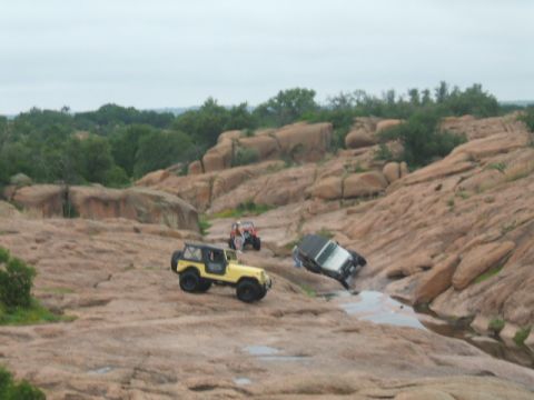 1995 Ford Bronco - Multiple off-road vehicles traverse a challenging rocky terrain with water features.