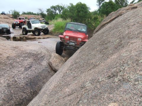 1995 Ford Bronco - Several off-road vehicles, including a red Jeep Wrangler, tackle a challenging rocky trail.